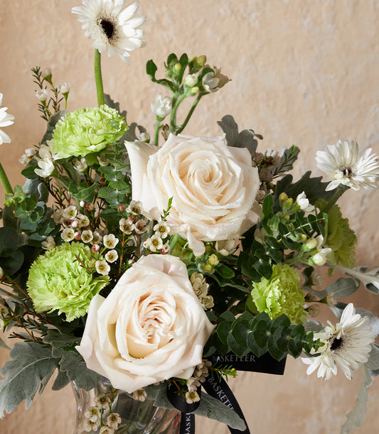 Ivory charm vase arrangement with white roses, gerbera daisies, and carnations in clear glass vase