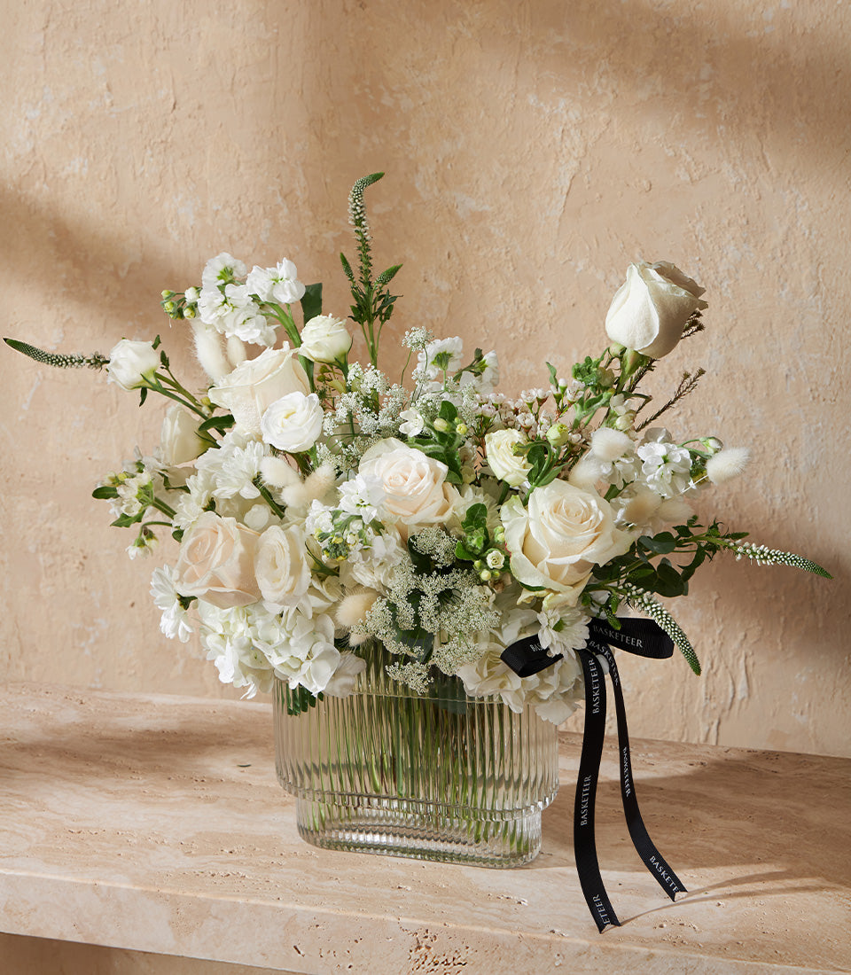 Lush white rose and hydrangea arrangement in ribbed glass vase with premium fresh flowers