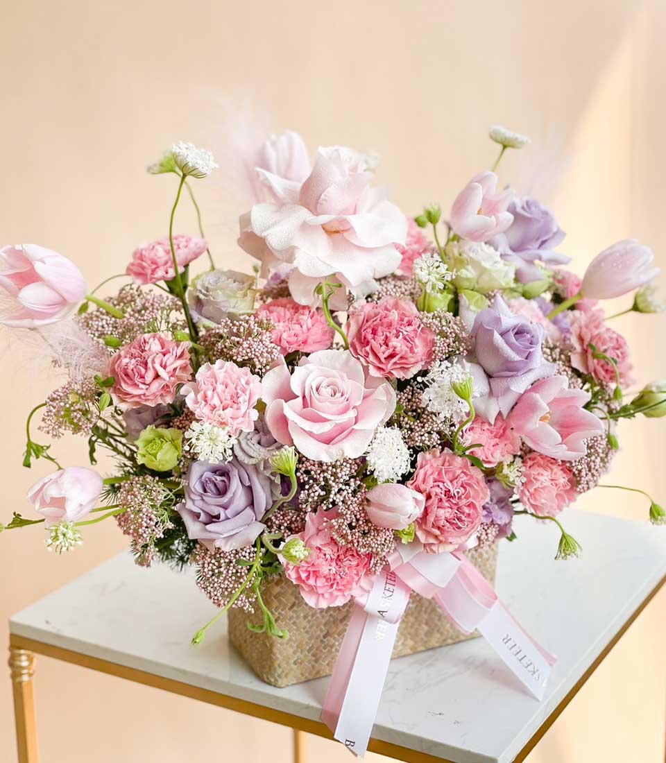 Pink and purple rose bouquet with tulips and carnations in woven basket, fresh get well flowers