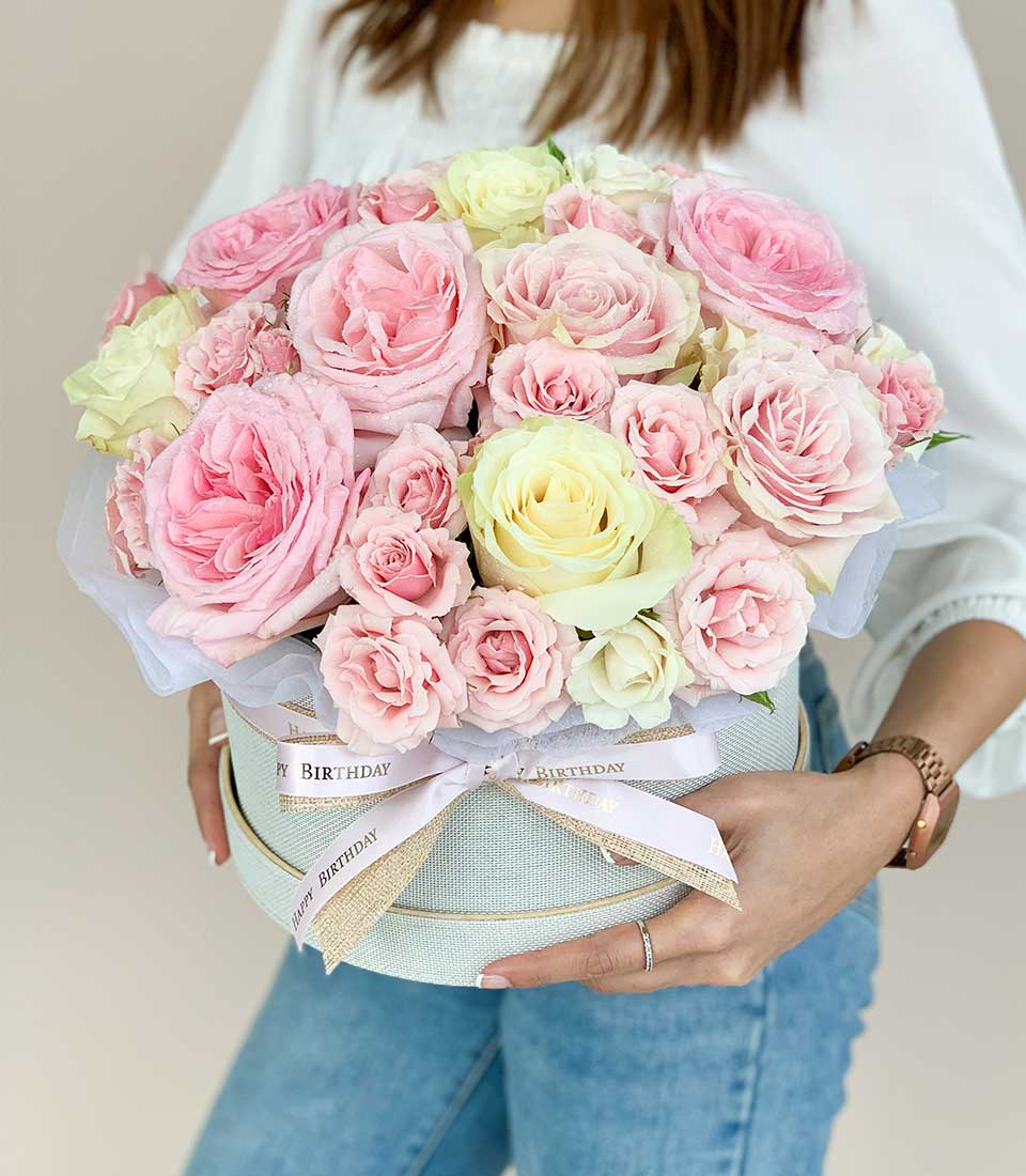 Fresh pink and cream roses in light blue hatbox with gold "Happy Birthday" ribbon
