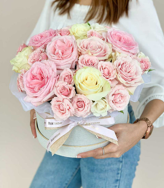 Fresh pink and cream roses in light blue hatbox with gold "Happy Birthday" ribbon