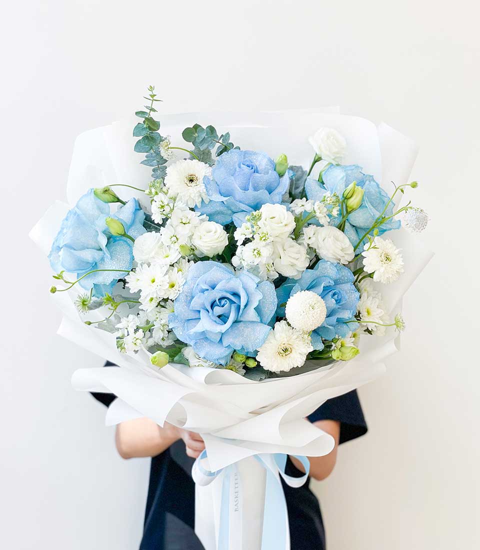Elegant blue roses and white blooms birthday bouquet with eucalyptus, wrapped in white paper