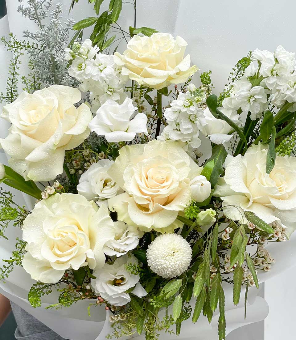 Pure white roses and lisianthus graduation bouquet with delicate stock flowers and silvery foliage