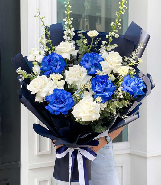 Elegant blue and white rose bouquet with eucalyptus wrapped in navy paper and ribbon