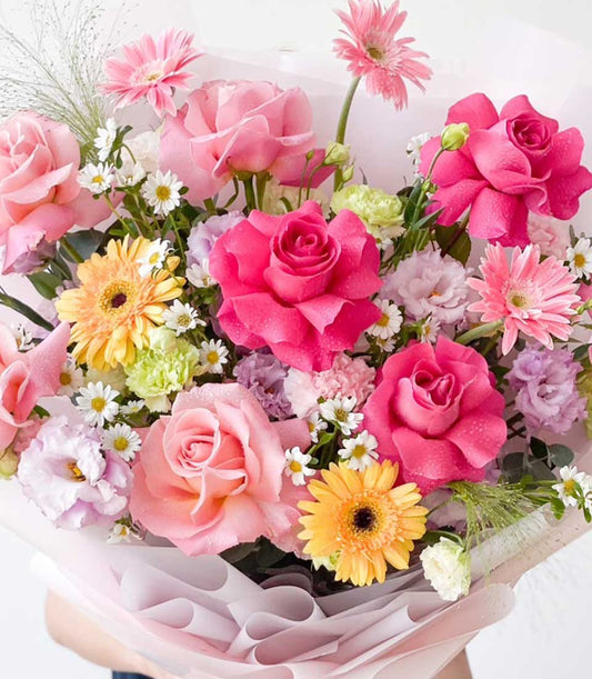 Fresh pink and yellow rose bouquet with gerbera daisies, wrapped in blush paper for birthdays