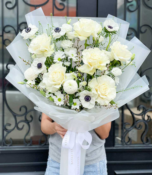 White rose and anemone graduation bouquet wrapped in premium paper with satin ribbon