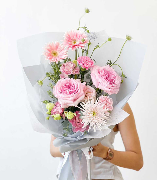 Fresh pink roses, gerberas, and carnations bouquet with eucalyptus and light blue wrap