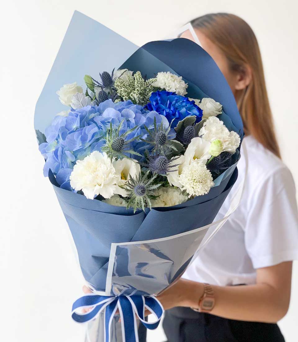 Vibrant blue hydrangea graduation bouquet with white carnations and thistles, navy wrapped