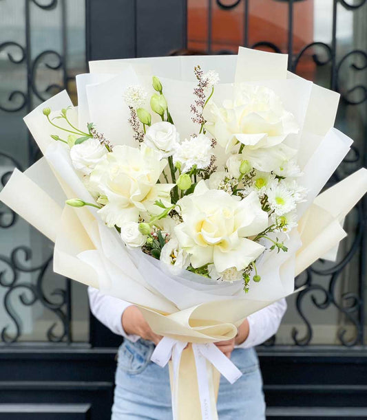 Elegant white roses and gardenias bouquet with cream paper wrapping and satin ribbon for graduation
