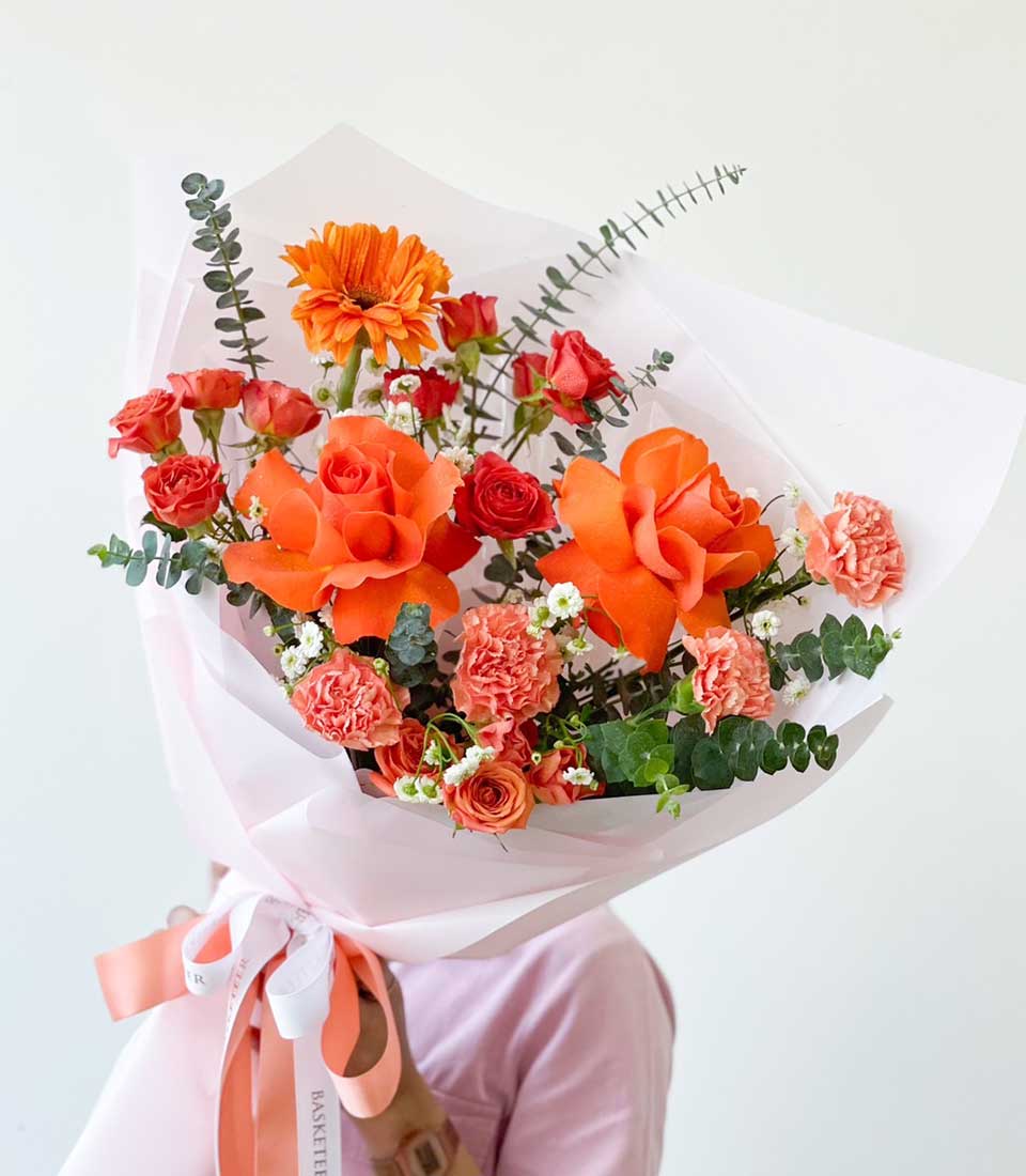 Warm amber and red rose bouquet with gerbera daisies, perfect for graduation congratulations