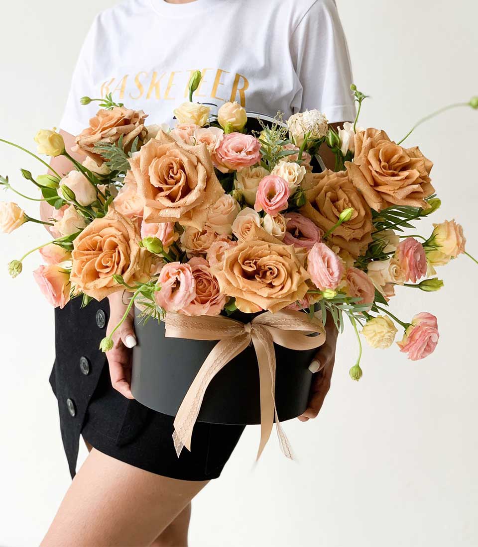 Peach and cream roses in black hatbox with champagne satin ribbon, luxury flower gift