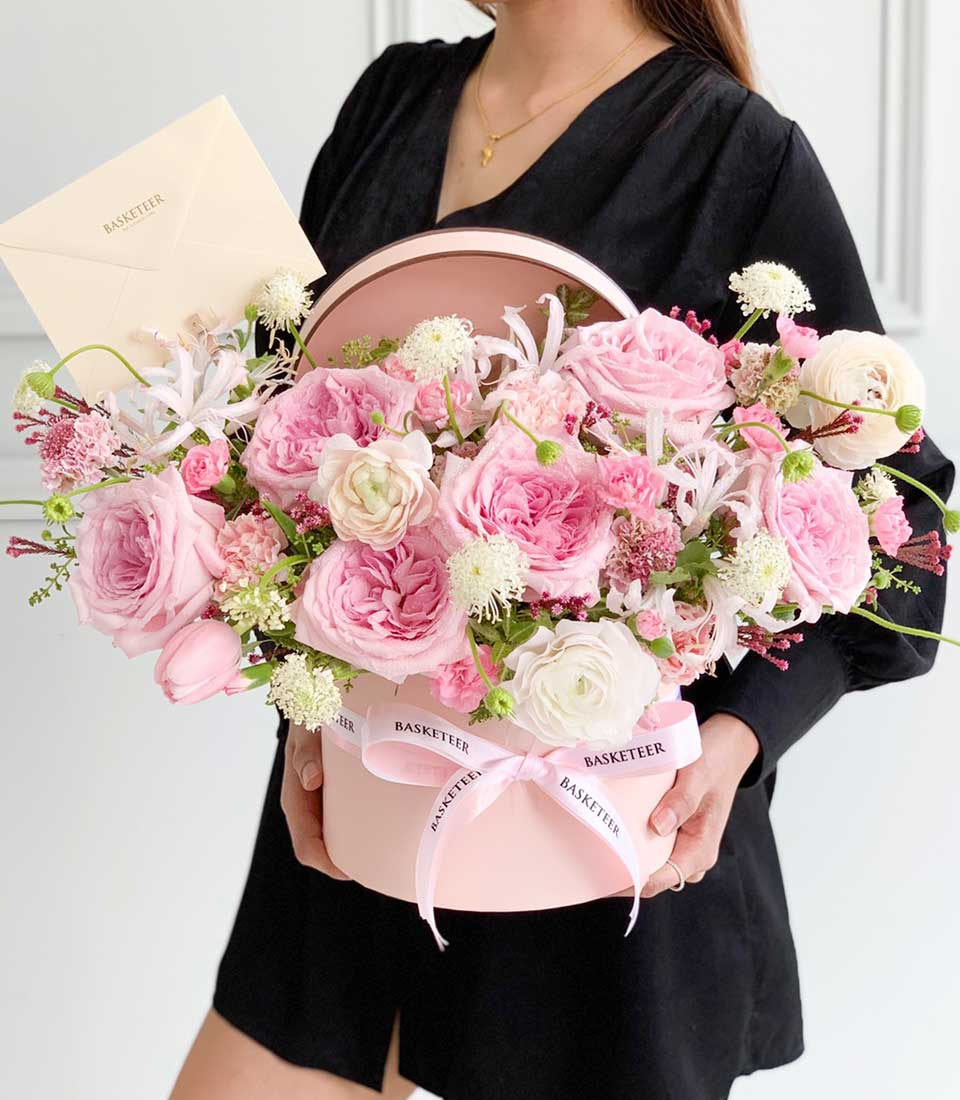 Fresh pink roses and ranunculus in a luxury hatbox with satin ribbon, perfect birthday gift for her