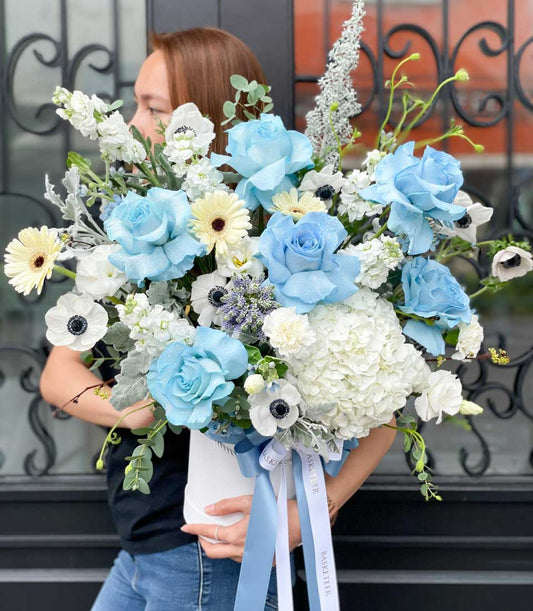 Light blue roses with hydrangeas and anemones in elegant white gift box, premium fresh flower arrangement