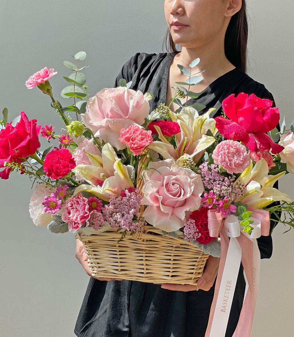 Large pink and red rose bouquet with white lilies in wicker basket, fresh birthday flowers gift