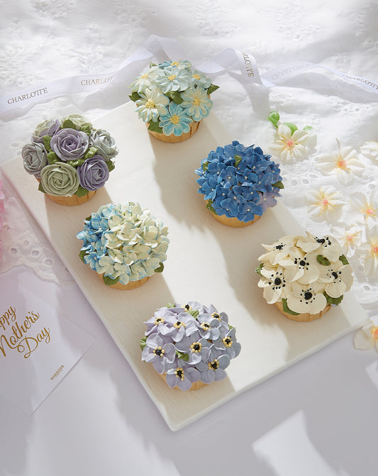 Serenity Blossom Mother's Day cupcakes with buttercream flower designs in pastel blues, purples, and cream