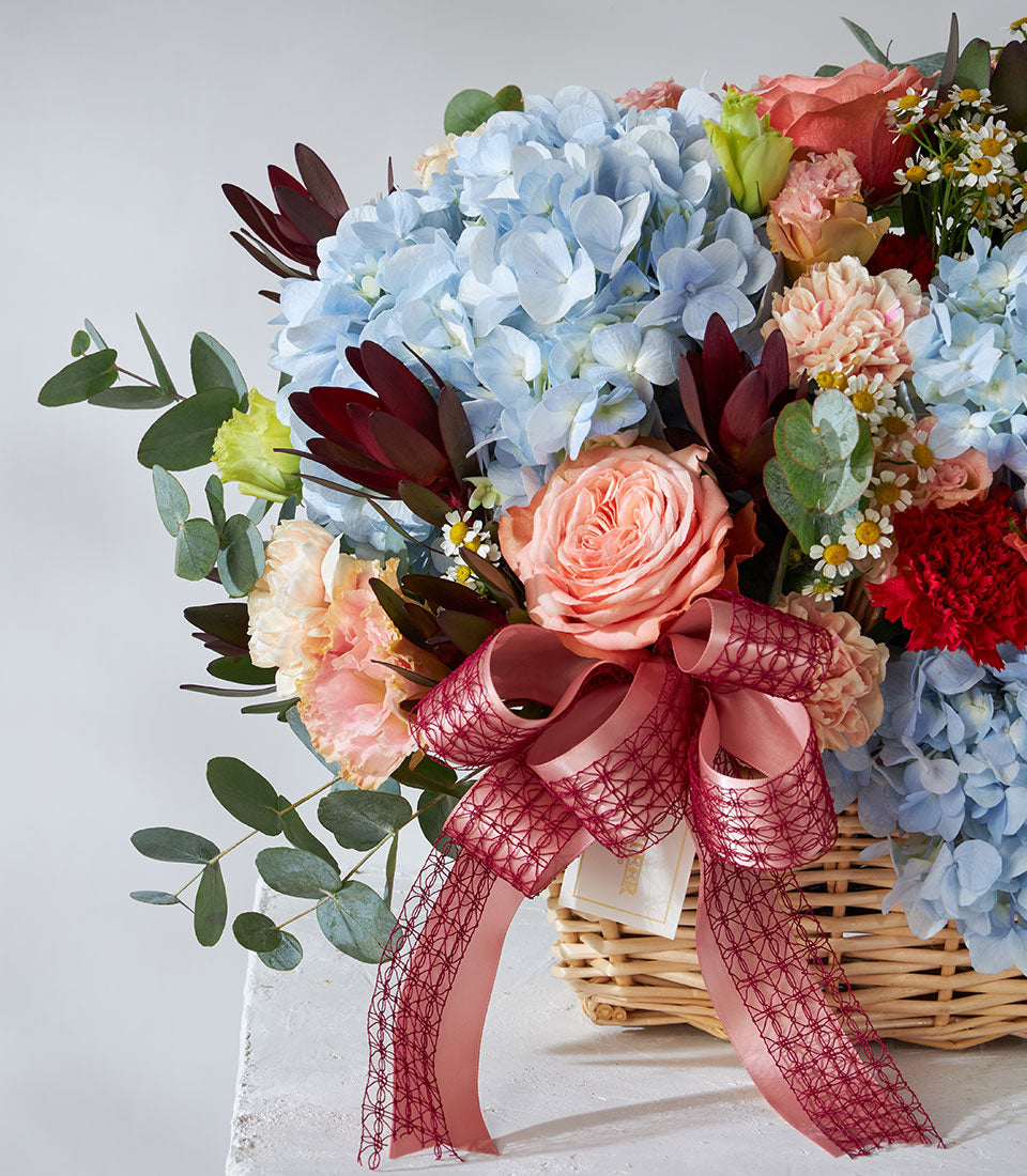 Vibrant get well flowers basket with hydrangeas, roses, carnations, and daisies in woven basket with ribbon