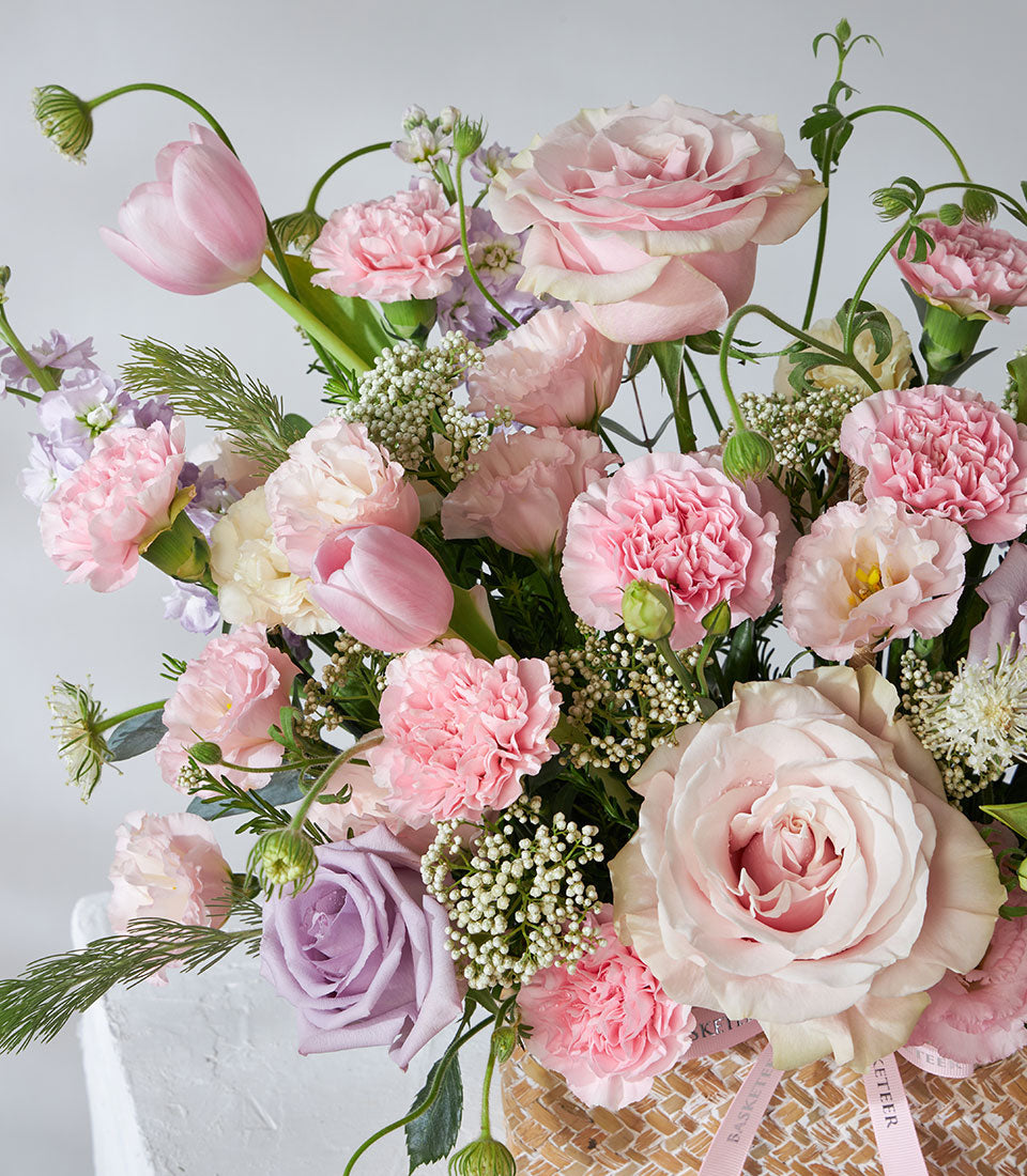 Lavender Bloom flower basket with pink roses, carnations, tulips, and white baby's breath in woven basket