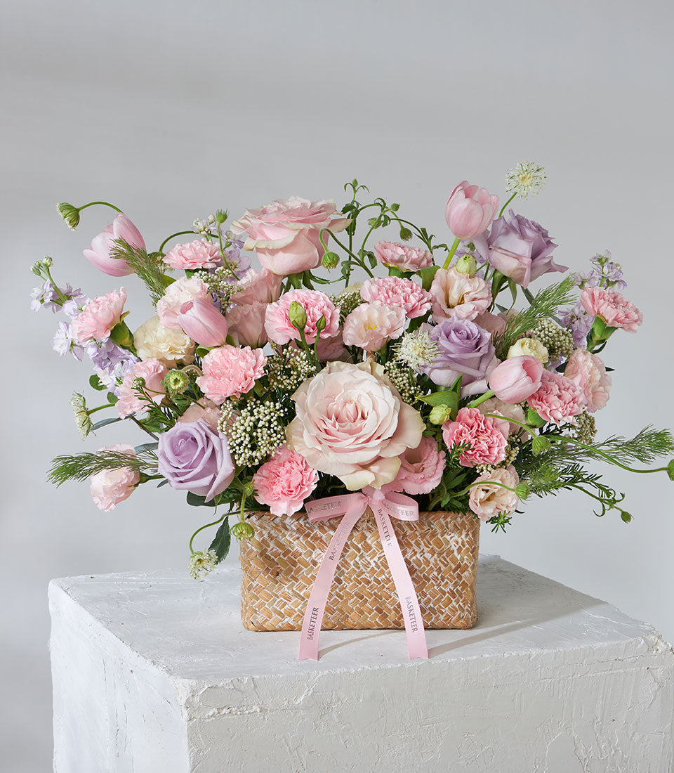 Lavender bloom flower basket with pink roses, tulips, carnations, and purple accents in woven basket