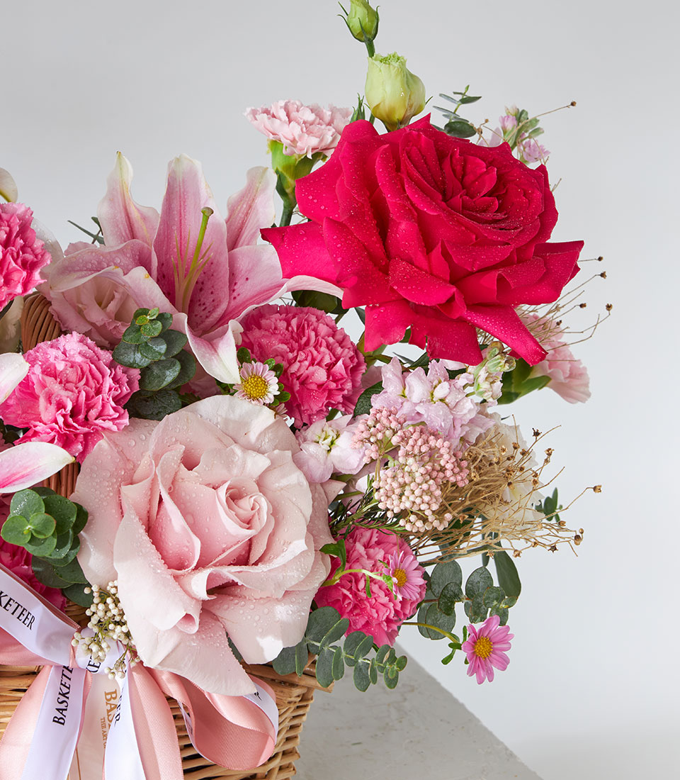 Pink and red floral arrangement with roses and lilies in woven wicker basket, birthday flowers gift