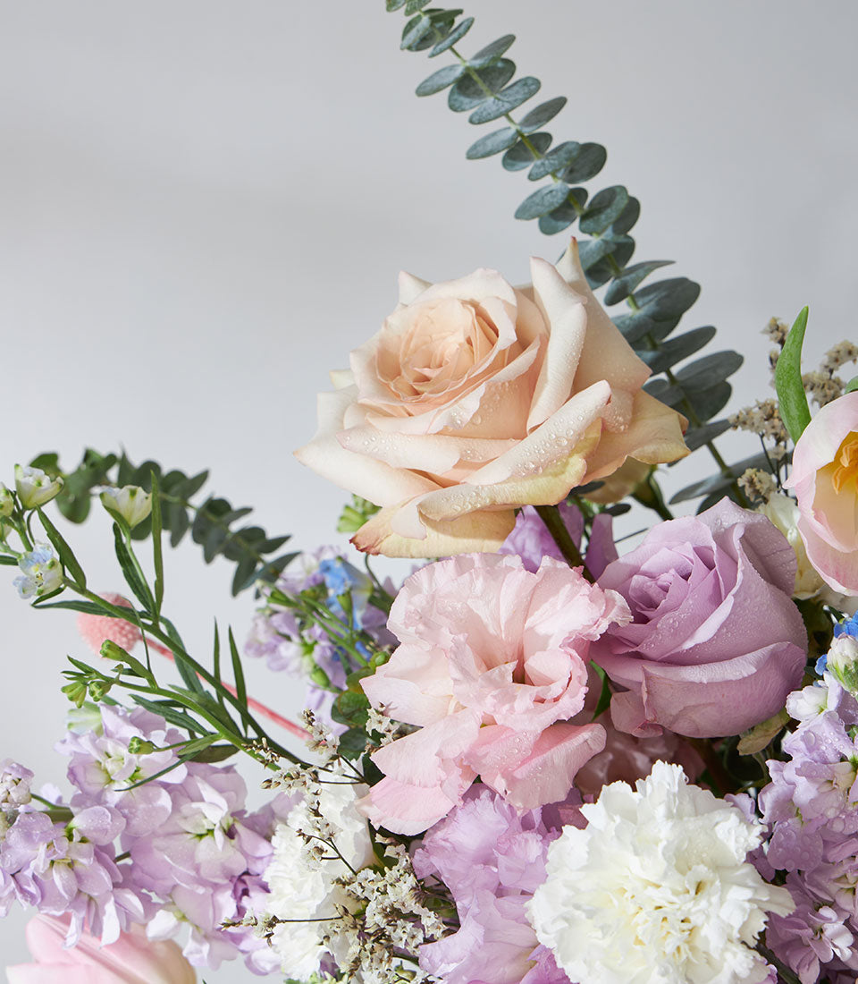 Soft pastel roses, lisianthus, and stock flower arrangement with fresh eucalyptus in a luxury gift basket