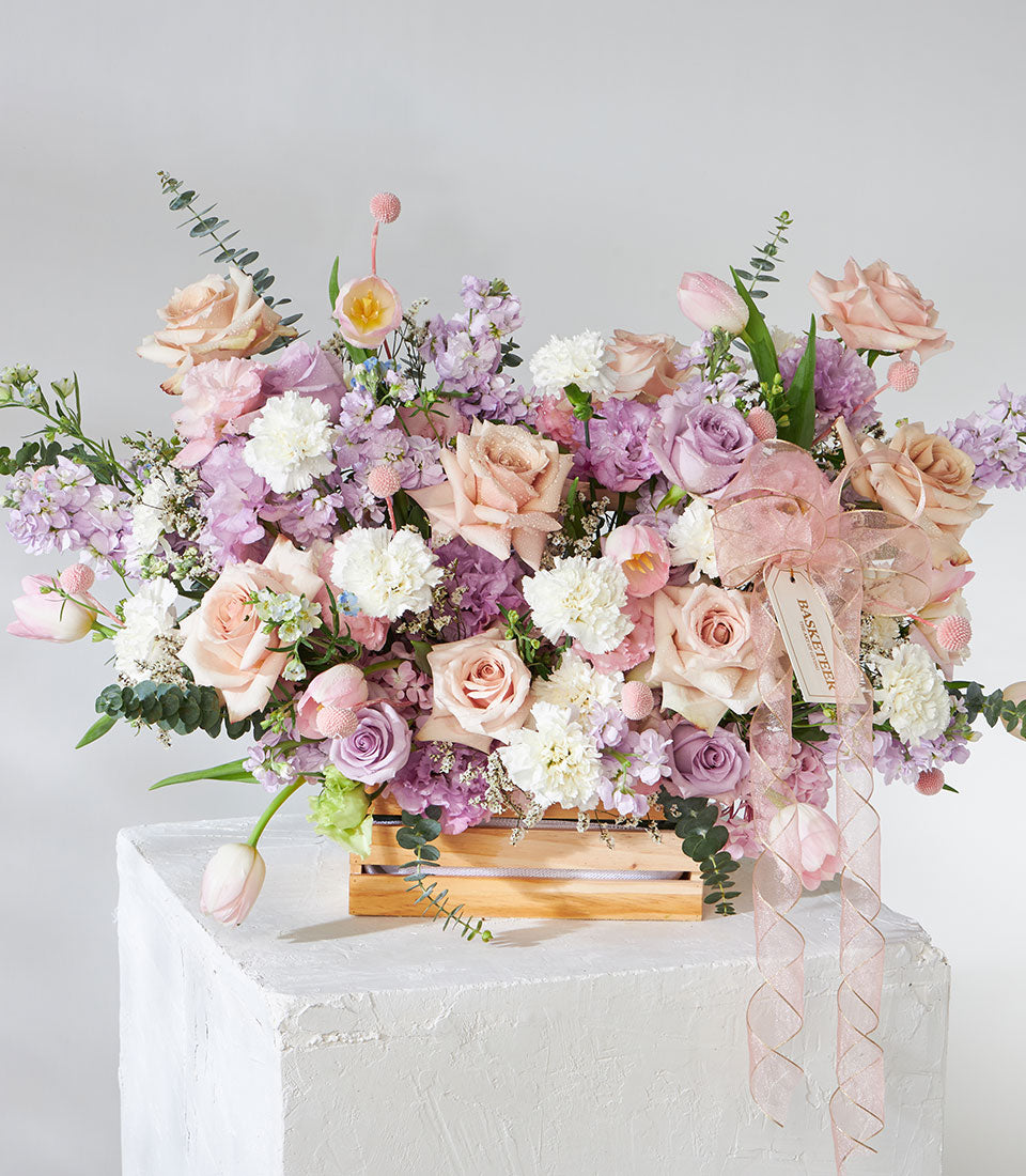 Pastel pink and lavender roses with white carnations in wooden crate, get well flowers arrangement