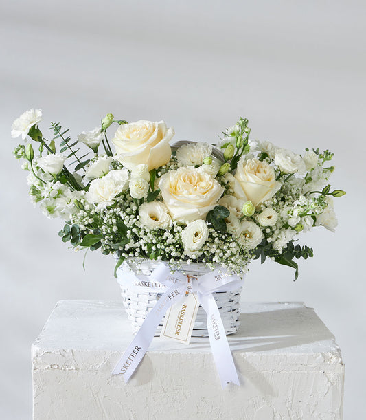 White and cream rose arrangement with lisianthus and baby's breath in woven basket