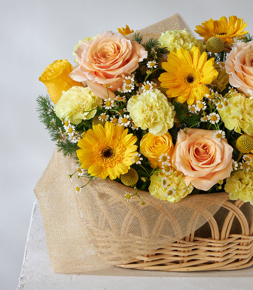 Yellow and peach roses with gerbera daisies in woven basket, fresh get well flowers with rustic burlap wrap