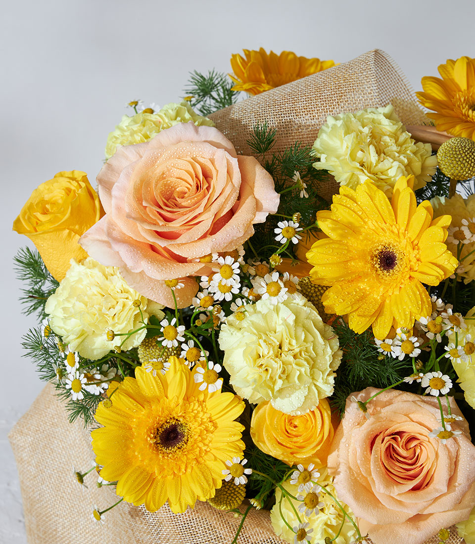Vibrant yellow, peach and white flower basket with roses, gerberas and carnations for get well wishes