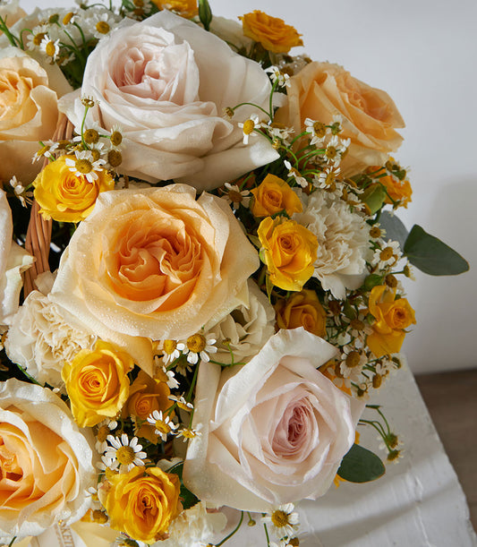 Sunshine Bloom Basket with yellow, peach, and cream roses, spray roses, carnations, and chamomile in woven basket