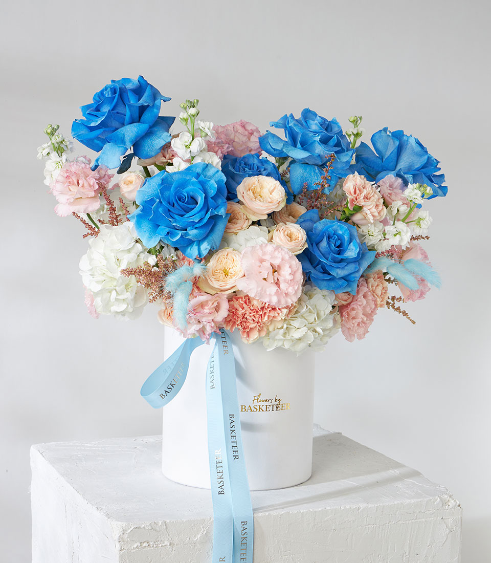 Tinted blue and pastel rose flower box with hydrangea, carnations, and dried accents in white cylinder