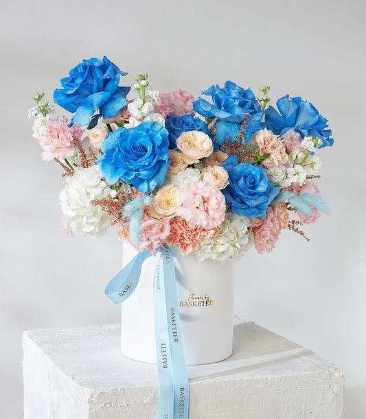 Tinted blue and pastel rose flower box with hydrangea, carnations, and dried accents in white cylinder