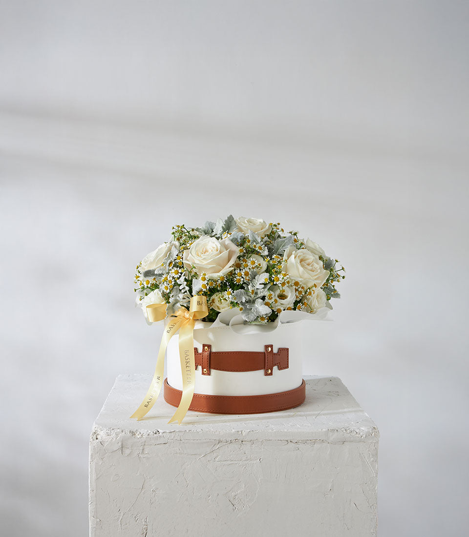 White roses and daisy flowers in luxury leather hatbox with golden ribbon bow