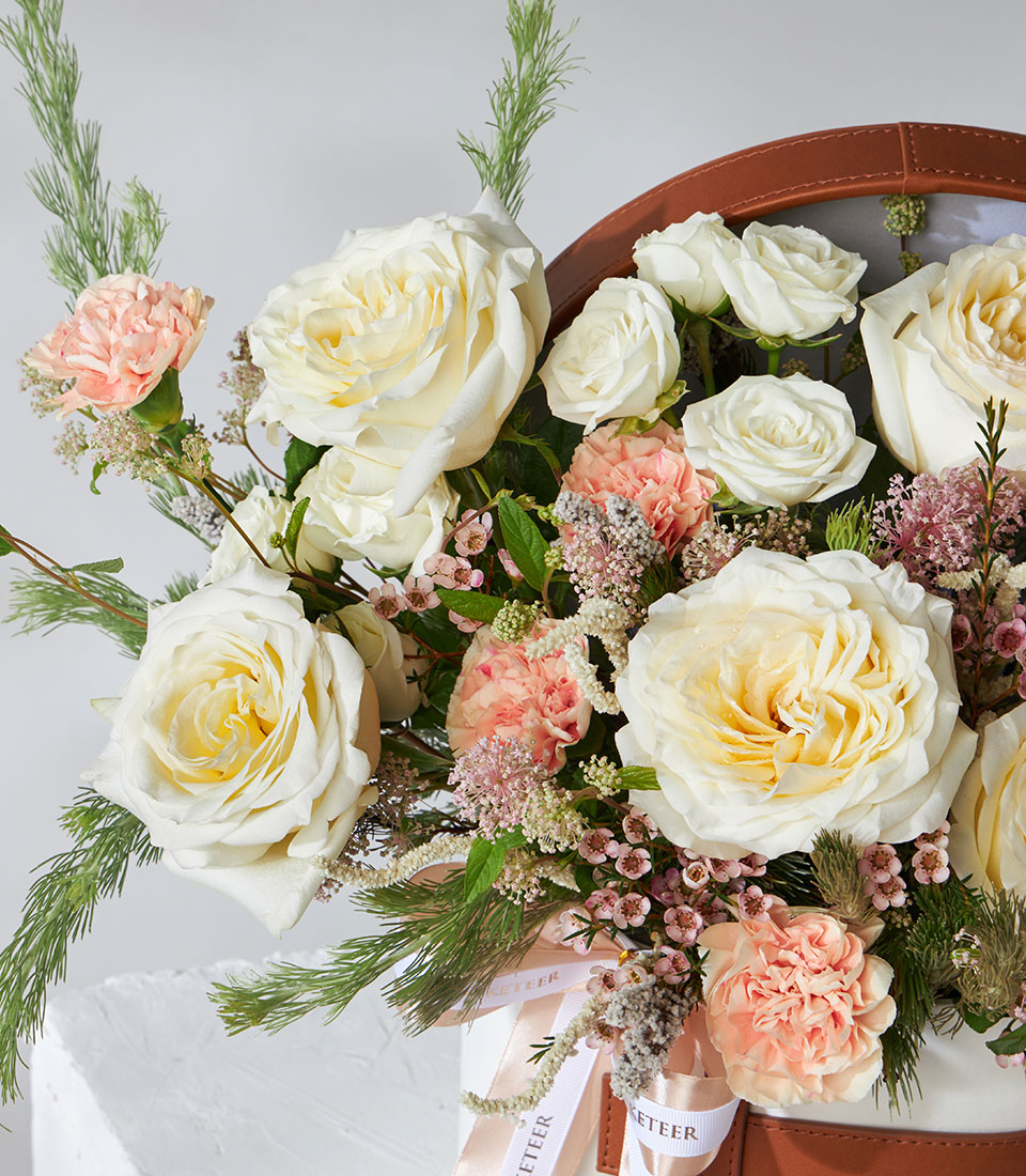 Candlelight roses and peach carnations in white leather flower box with pink ribbon