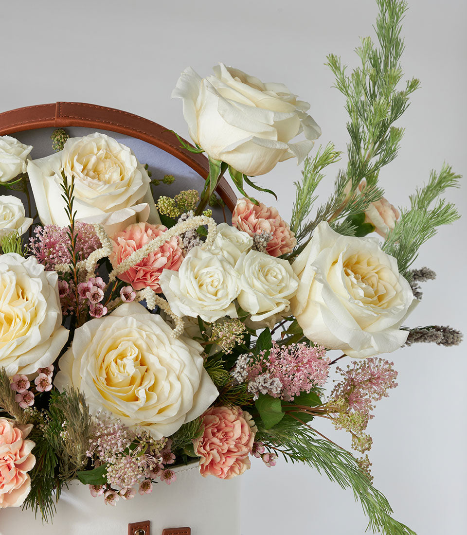 Luxury white and peach carnation roses in leather flower box with green foliage