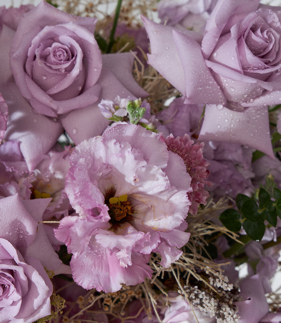 Light purple roses and pink eustoma with lavender hydrangea in fresh floral basket arrangement