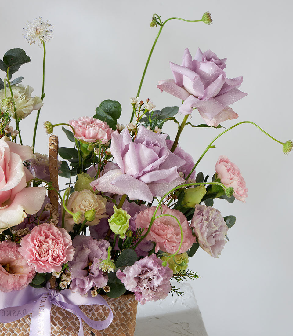 Light purple roses and pink carnations in woven basket with purple satin bow, get well flowers arrangement