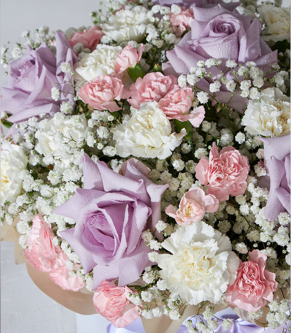 Lavender roses and pastel carnations with baby's breath in beige paper box arrangement