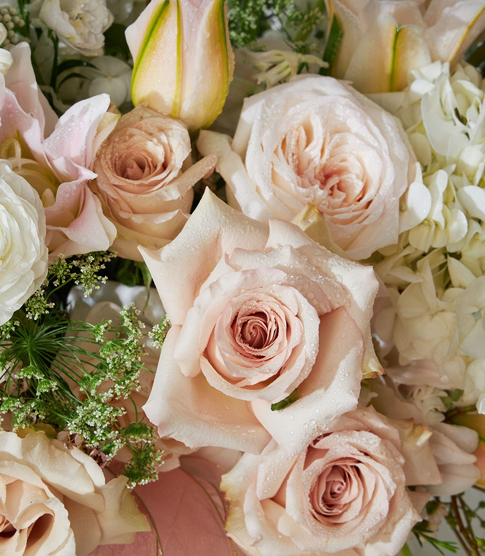 Luxury floral basket with quicksand roses, white lilies, ranunculus, and hydrangea in soft pink tones