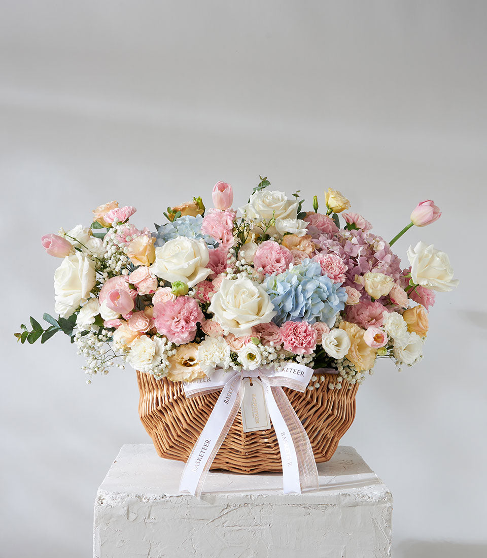 Pastel pink and white roses with hydrangeas in woven wicker gift basket, perfect for birthdays and celebrations