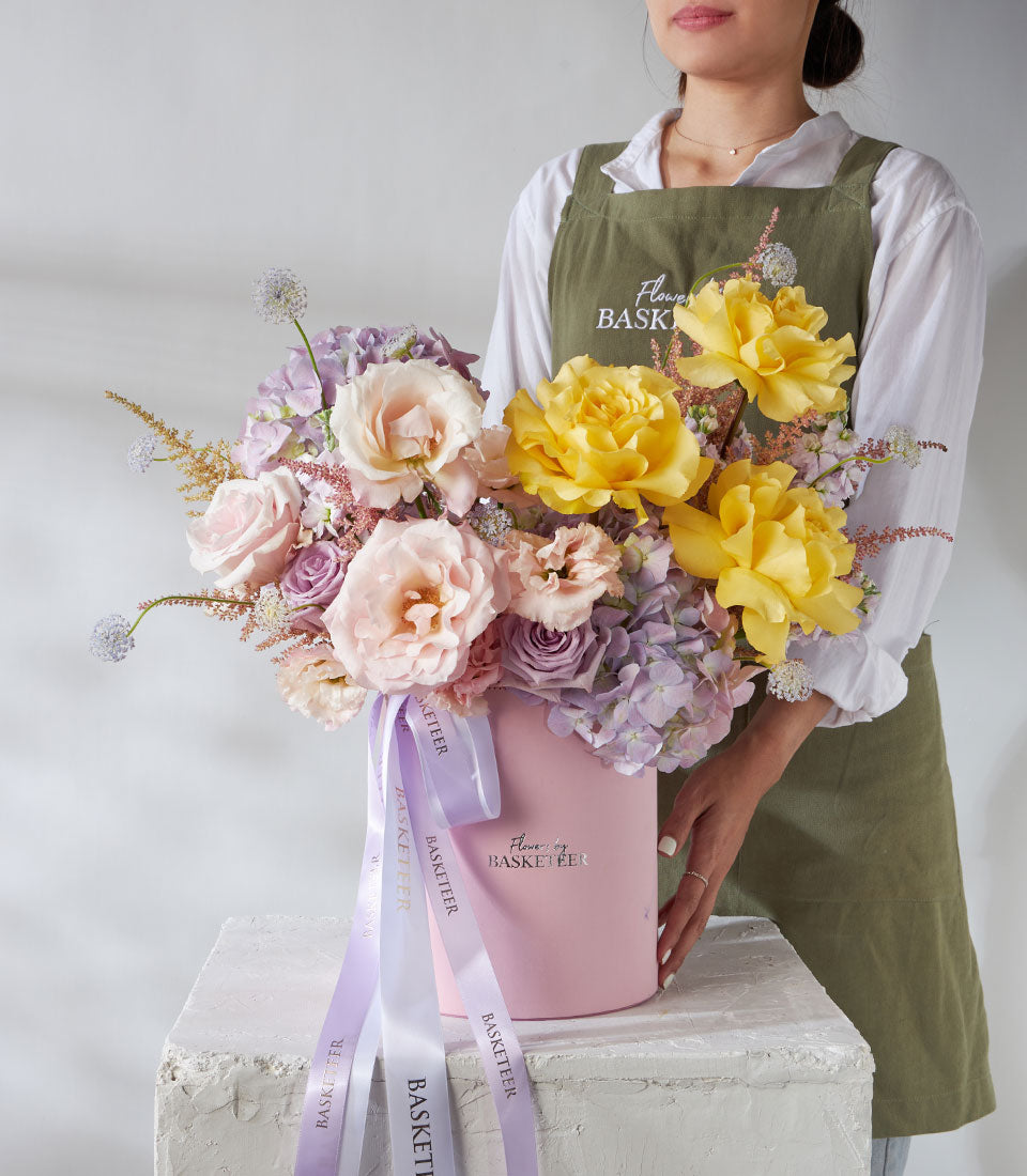 Premium velvet flower box with yellow roses, pink Cloud, Ocean Song blooms and purple hydrangeas in pink hatbox with satin