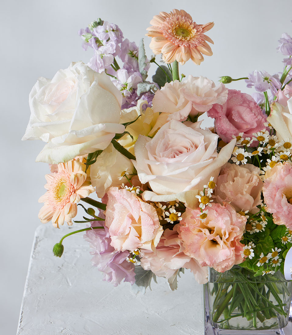 White O'Hara roses with peach garden flowers in square glass vase