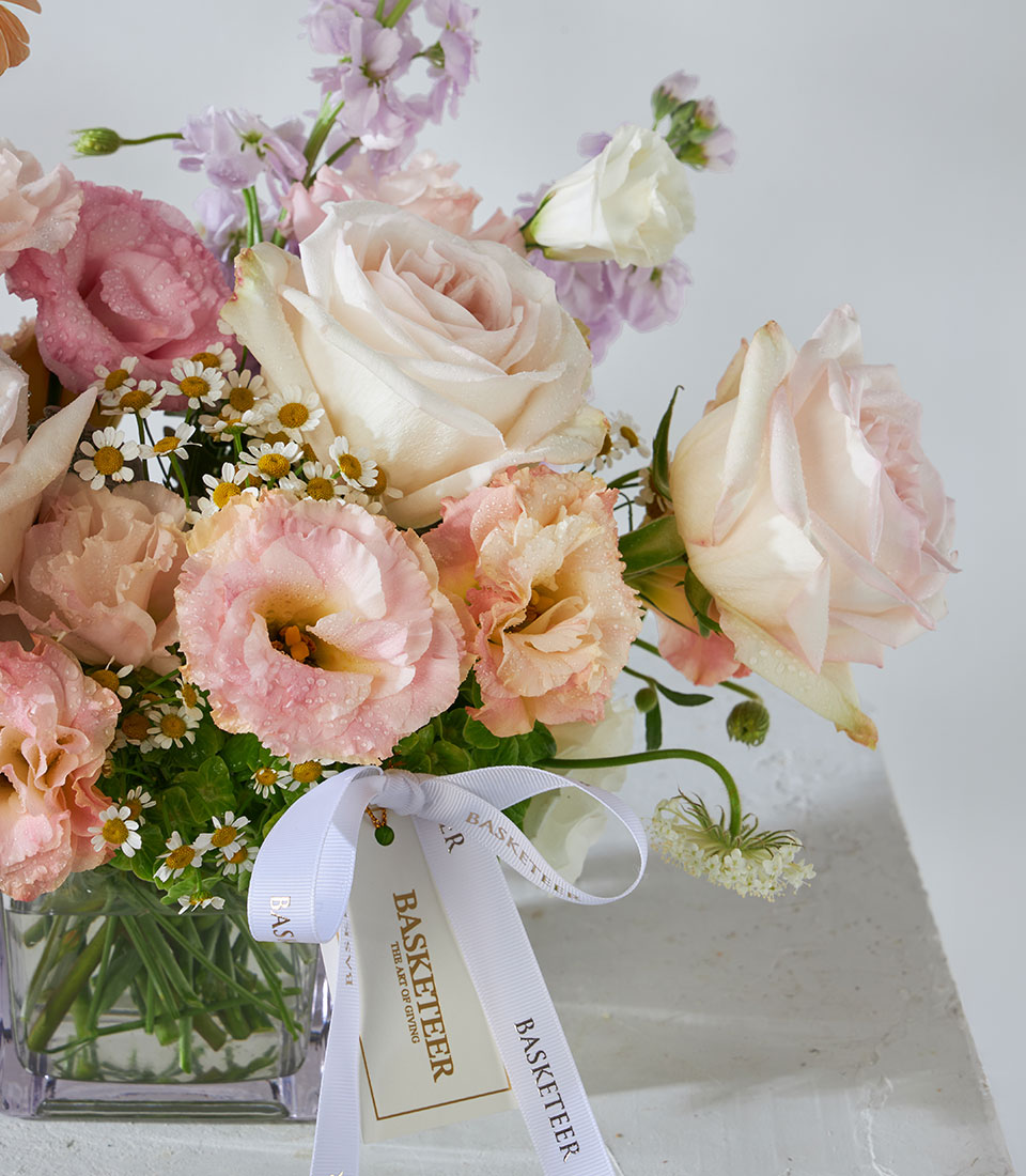 White O'Hara roses and peach garden flowers with lisianthus and stock in square glass vase