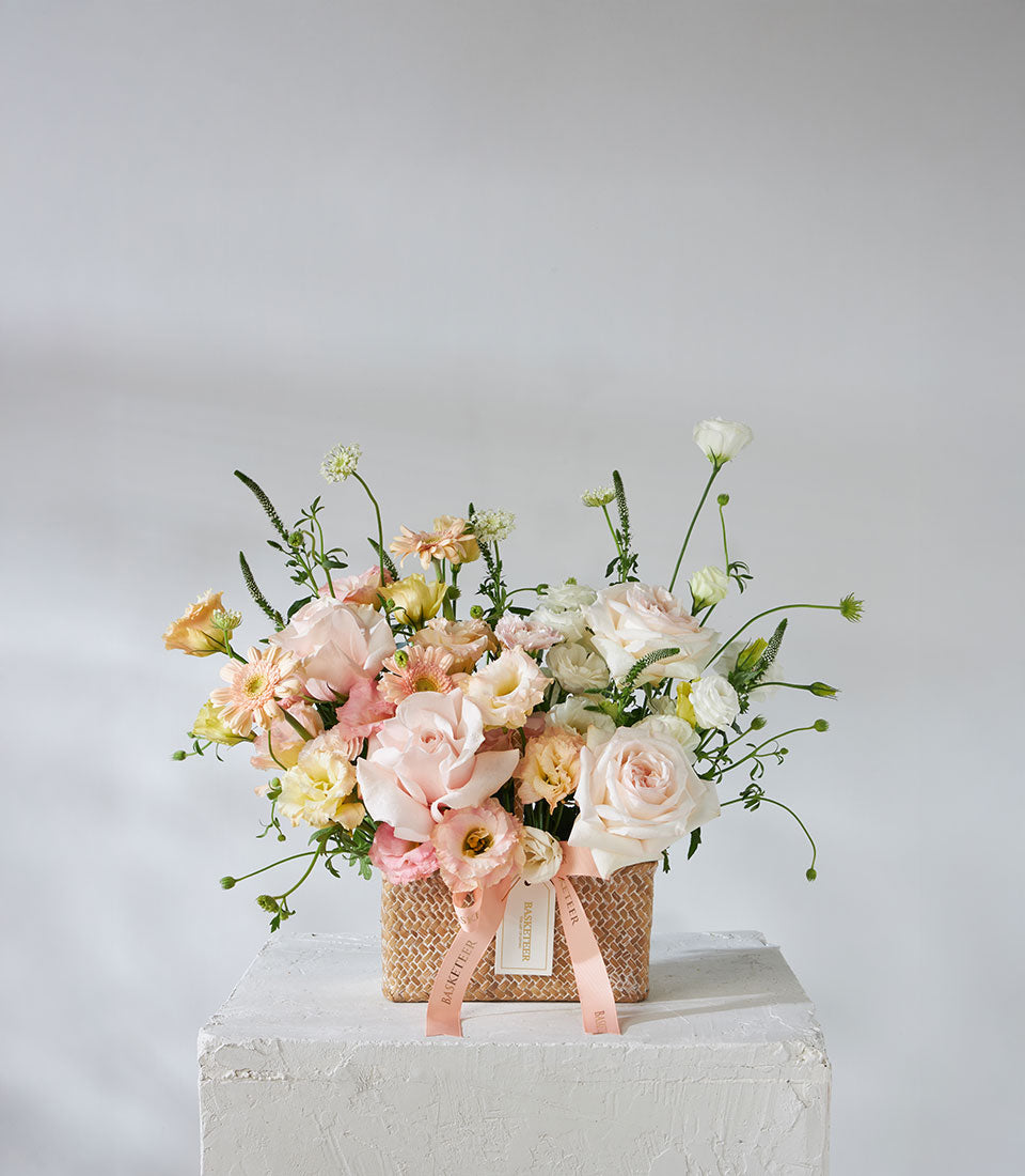 Pastel pink and white O'Hara roses with peach gerberas in woven basket, birthday flowers arrangement