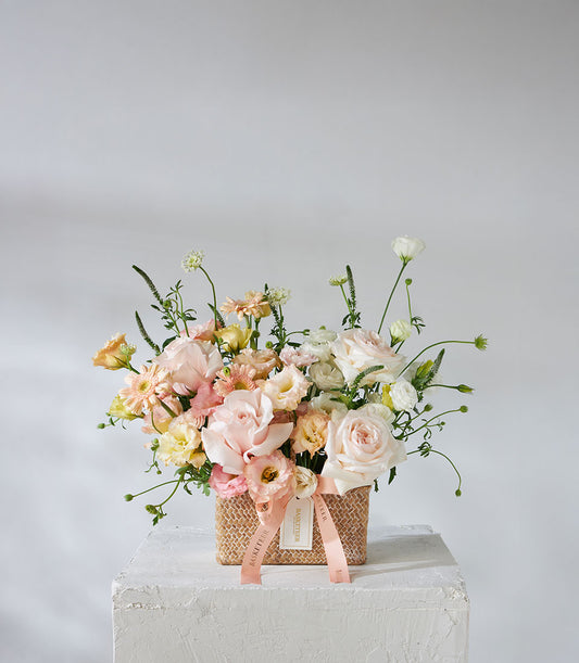 Pastel pink and white O'Hara roses with peach gerberas in woven basket, birthday flowers arrangement