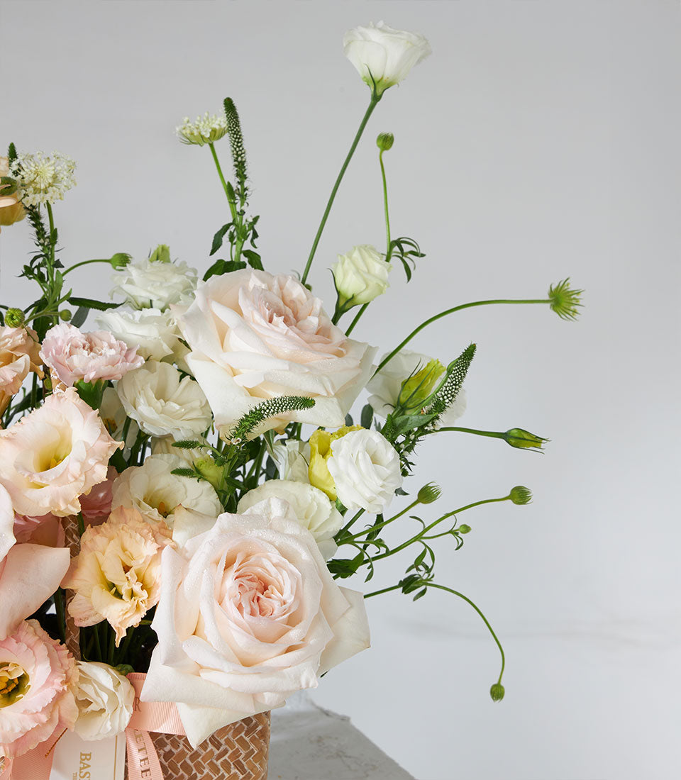 Pastel white and pink rose bouquet with lisianthus in woven basket, fresh birthday flowers