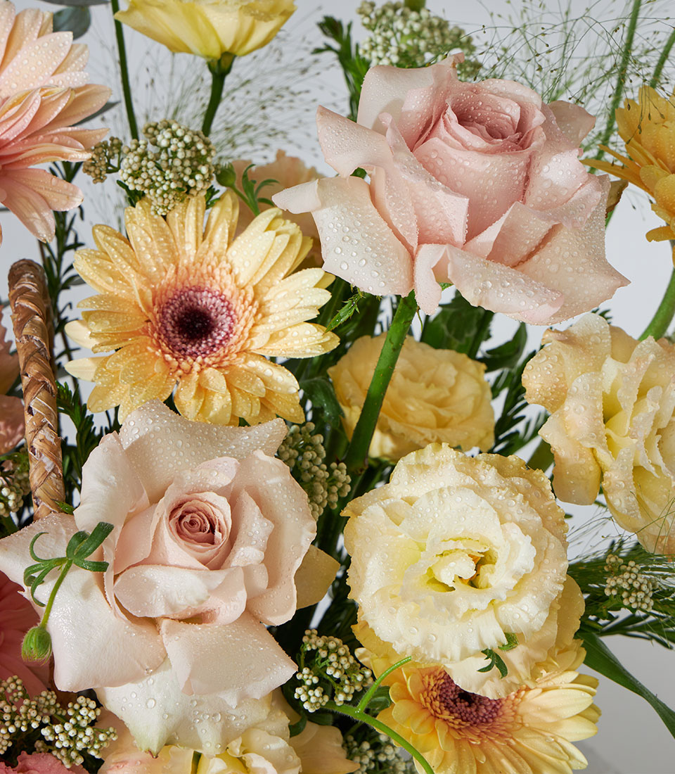 Pastel pink roses and yellow daisies in a woven basket arrangement, birthday flowers gift