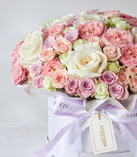 Playa Blanca roses and pastel spray roses in white cylindrical hatbox with lavender ribbon