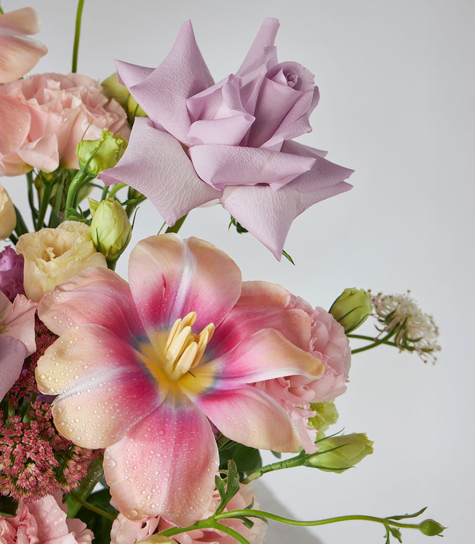 Pastel rose and tulip arrangement with carnations and lisianthus in woven basket