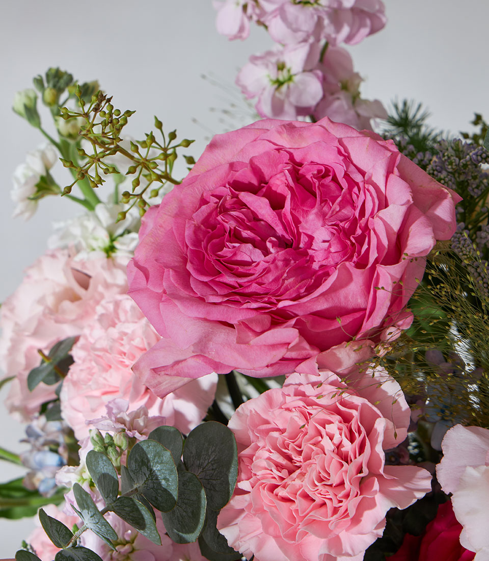 Pink and white rose garden basket with carnations, stock flowers, and eucalyptus greenery