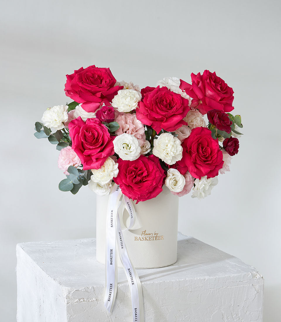 Luxury red roses and white lisianthus in white cylindrical gift box with ribbon